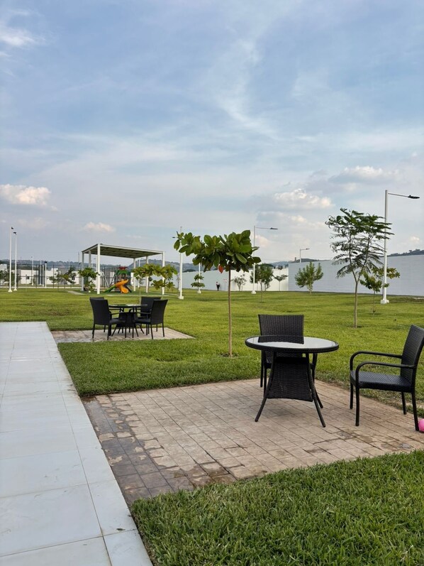 An outdoor seating area with tables and chairs, a covered play structure, and a view of a body of water.