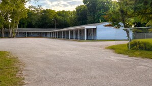 A building with a covered outdoor area, a gravel path, and a chain-link fence. - Cozy Florida Stay in Bradenton (Bradenton)