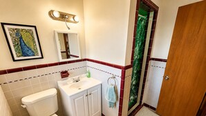 A bathroom with a toilet, sink, mirror, and a framed picture on the wall. - Cozy Florida Stay in Bradenton (Bradenton)