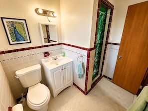 Ein Badezimmer mit Toilette, Waschbecken, Spiegel und einem gerahmten Bild an der Wand.