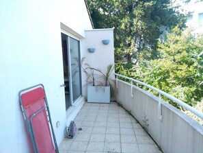 A balcony with a potted plant, a red chair, and a window. - A summer getaway with a Mediterranean flair (Montpellier)
