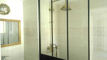 A bathroom with a glass shower enclosure, a mirror, and a toilet.