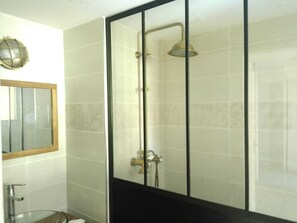 Ein Badezimmer mit Glasdusche, Spiegel und Toilette.