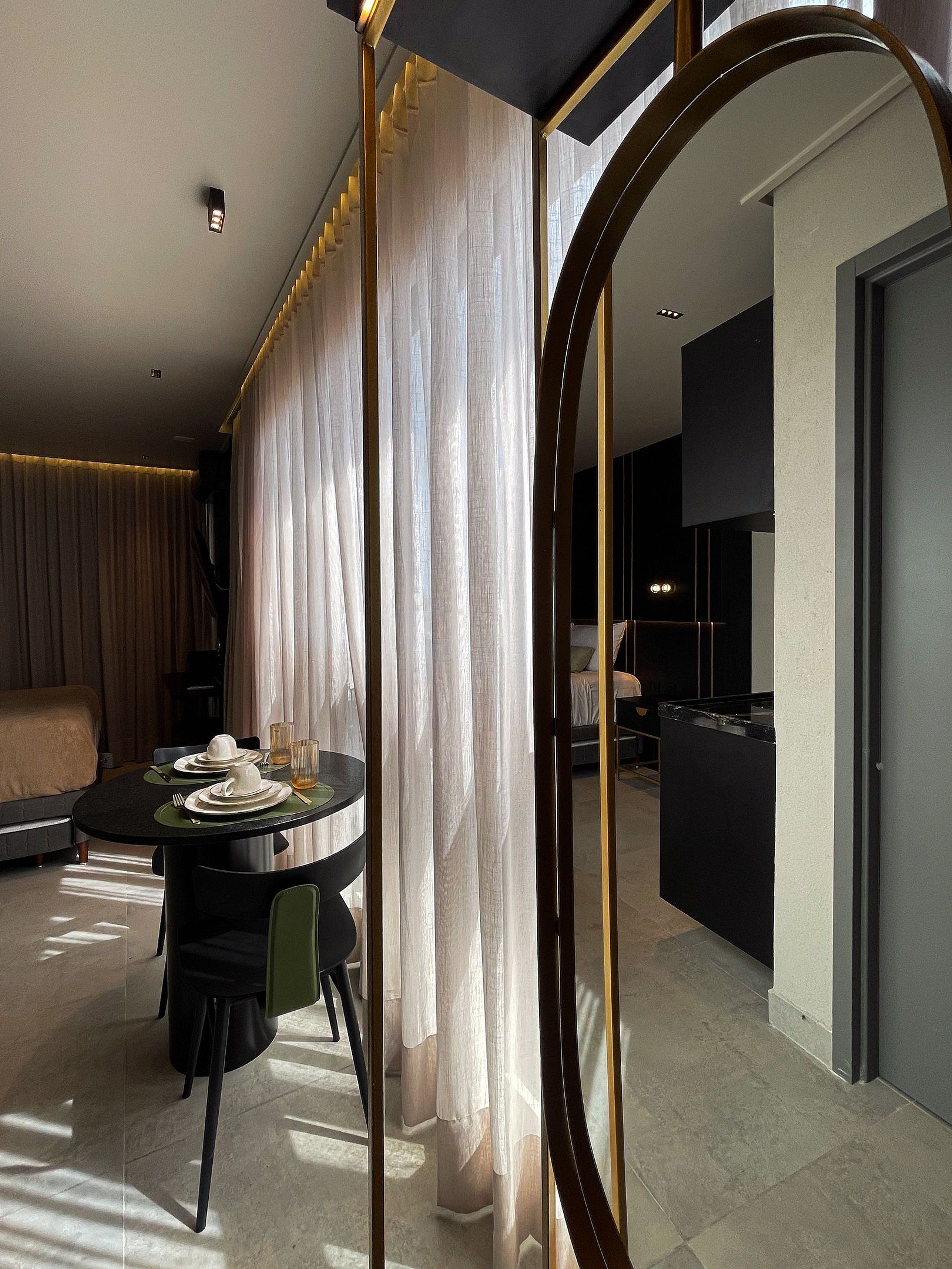 A modern hotel room with a dining area, a bed, and a bathroom.