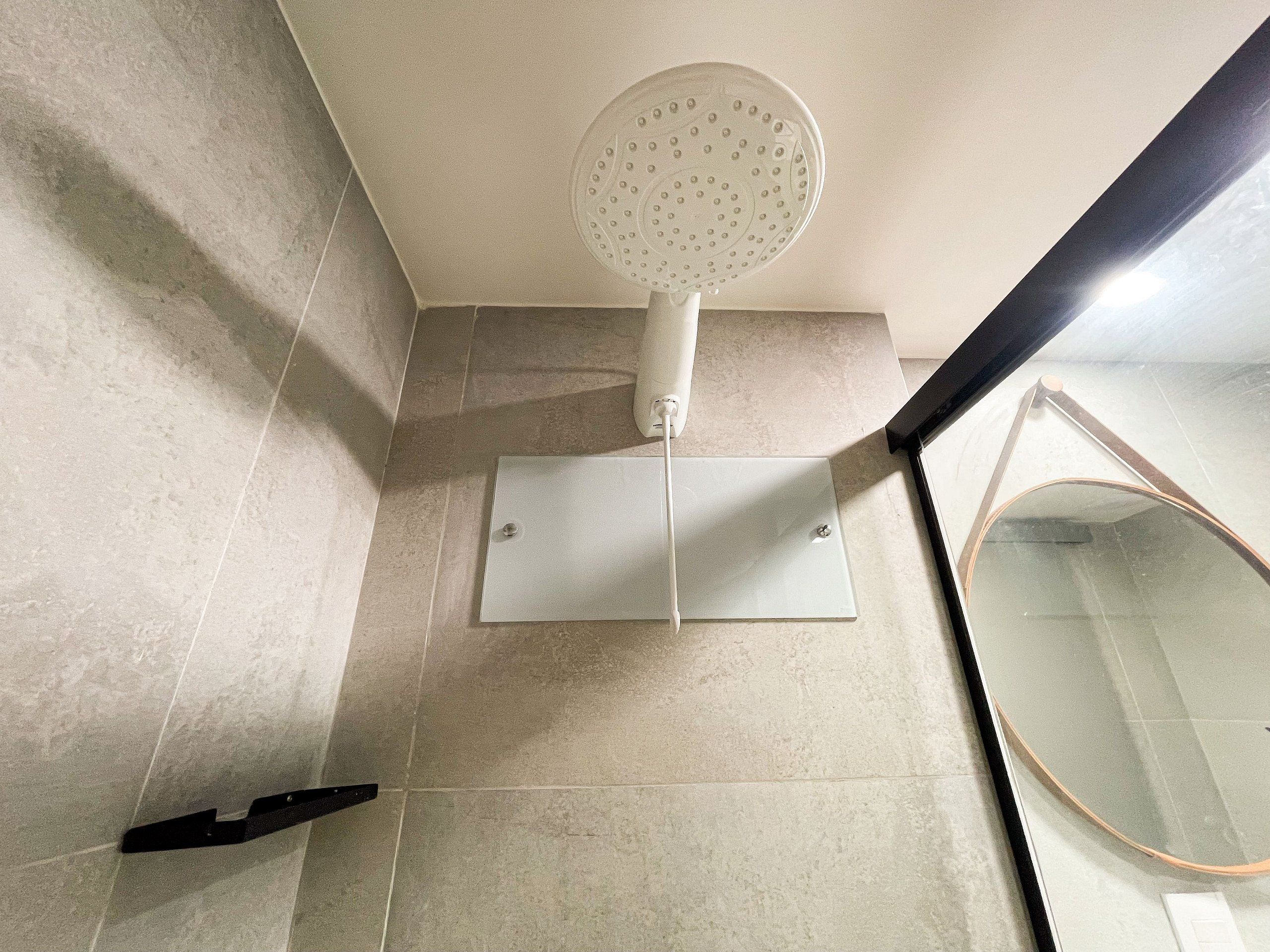 A bathroom with a shower, a mirror, and a towel rack.