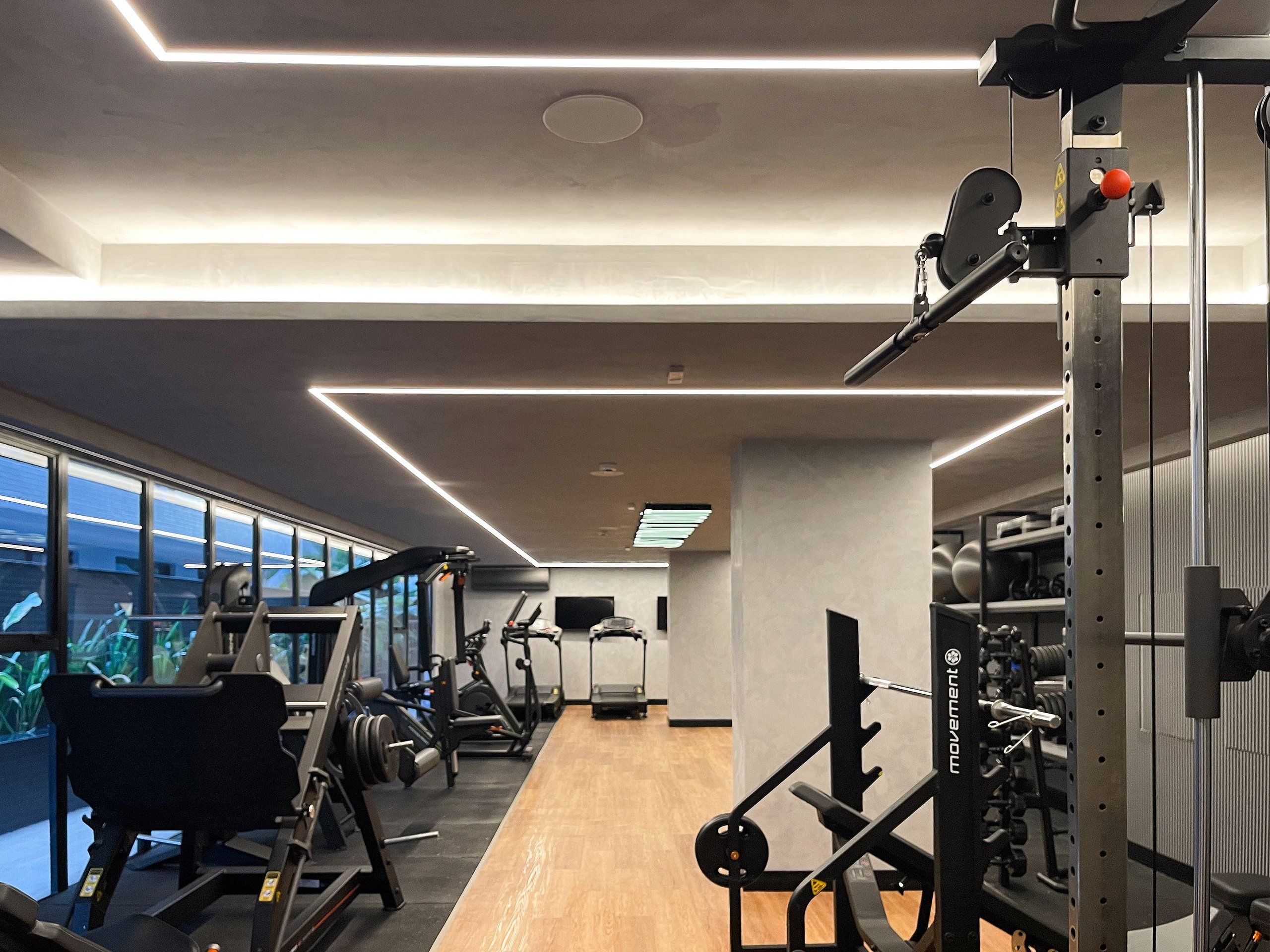 A gym with exercise equipment, a wooden floor, and large windows.