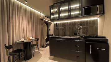Una cocina moderna con armarios oscuros, un microondas integrado y una mesa de comedor redonda con sillas.