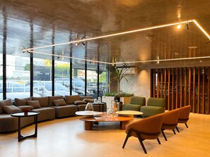 A modern interior with a seating area, large windows, and a plant.