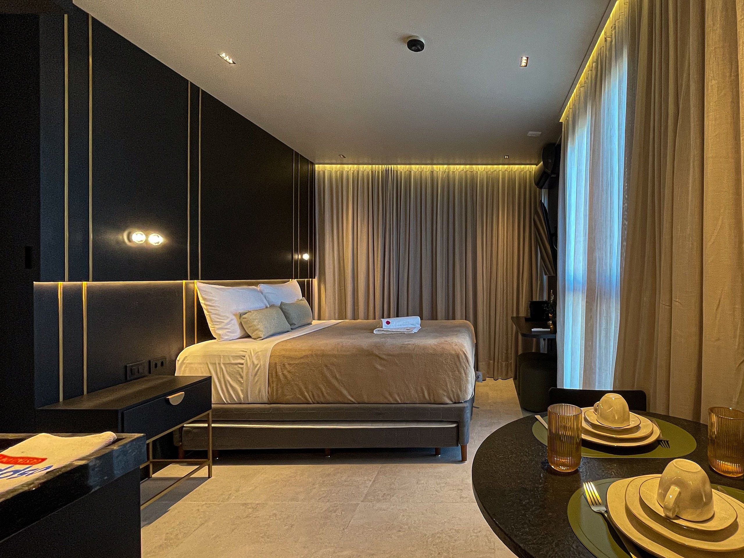 Una camera d'albergo moderna con un letto, un comodino e un'area pranzo con stoviglie.