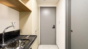 A narrow hallway with a kitchen area on one side, featuring a sink and cabinets.