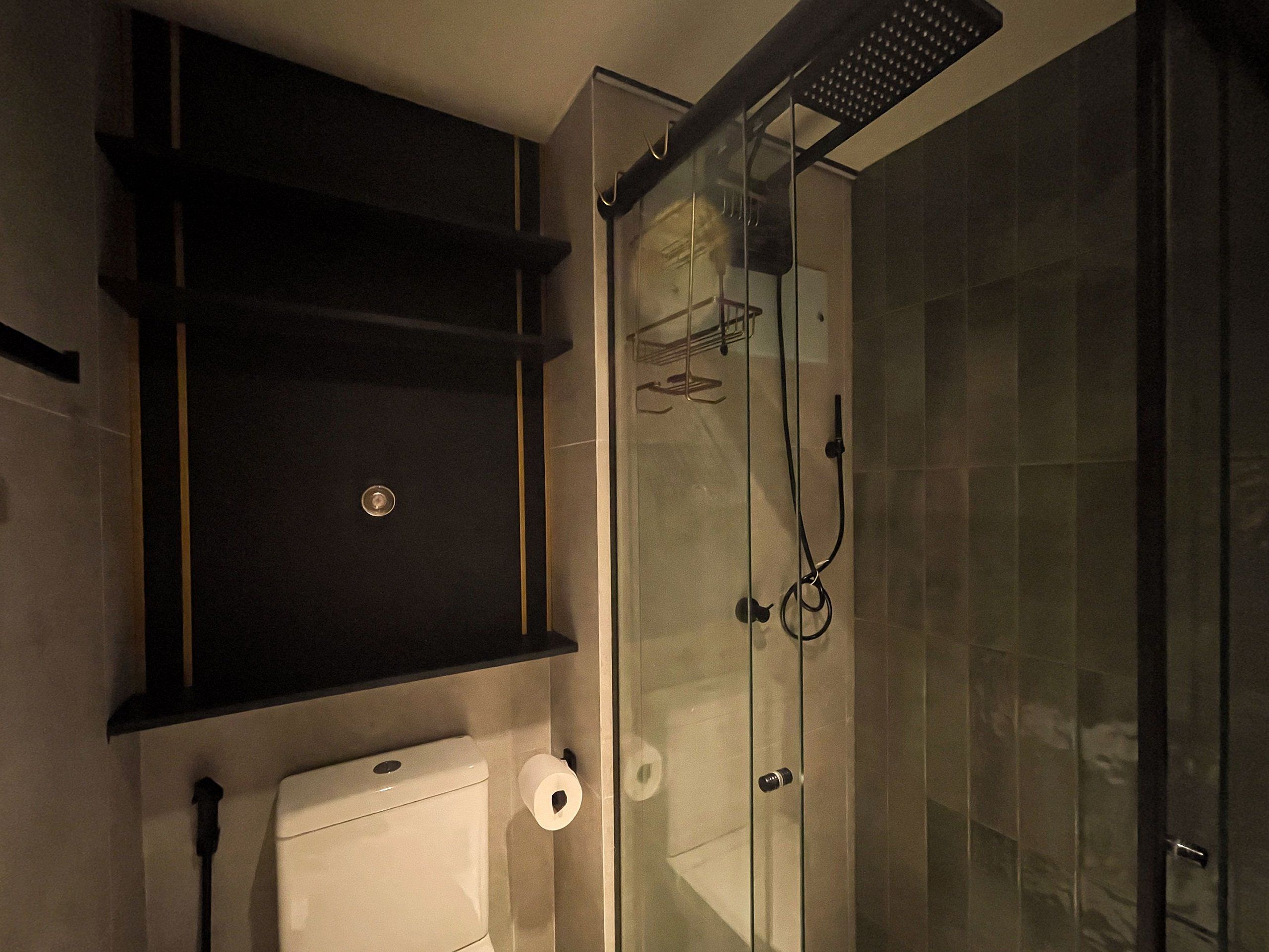 A bathroom with a glass shower enclosure, a toilet, and a towel rack.