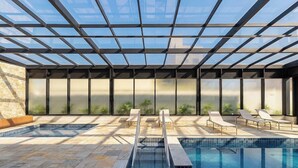A modern indoor swimming pool with glass ceiling, lounge chairs, and a stone wall. - Apt. in Condo. w/ Pool & City View Sru2109 (Campinas)