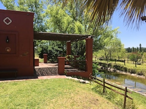 A red building with a pergola entrance, a small pond, and a wooden fence.