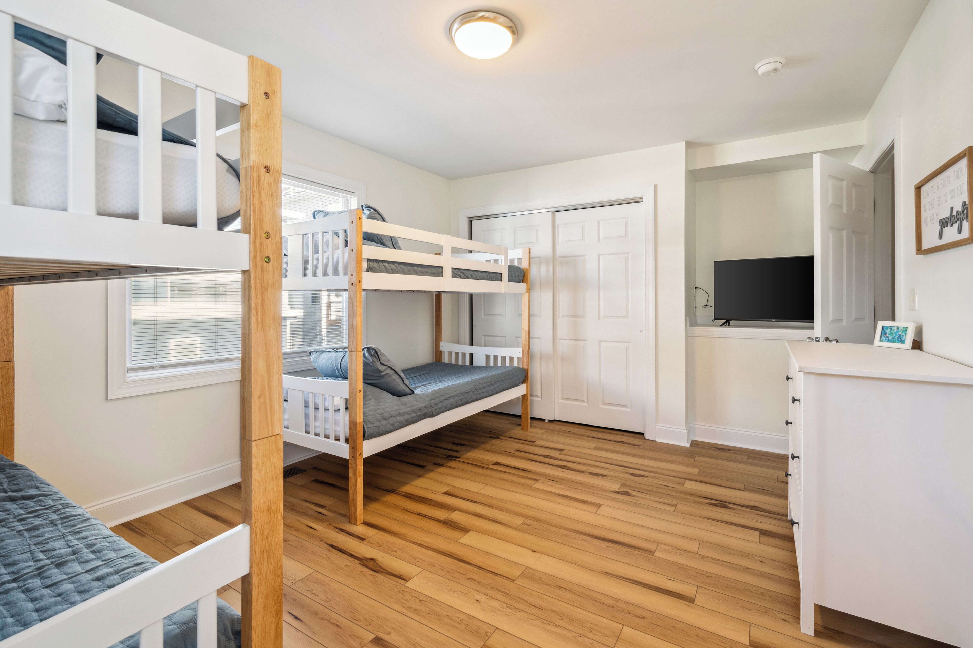 Une chambre avec des lits superposés, un bureau, une télévision et une armoire.