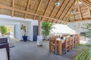 An open-plan dining area with a thatched roof, wooden furniture, and potted plants. - Family oasis near the sea - La Cruz Encantada 2A (La Cruz de Huanacaxtle)