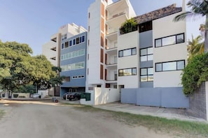 A multi-story residential building with a parking area in front. - Family oasis near the sea - La Cruz Encantada 2A (La Cruz de Huanacaxtle)