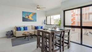 A modern living room with a dining area, a ceiling fan, a large window, and a painting on the wall. - Family oasis near the sea - La Cruz Encantada 2A (La Cruz de Huanacaxtle)