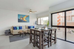 A modern living room with a dining area, a ceiling fan, a large window, and a painting on the wall. - Family oasis near the sea - La Cruz Encantada 2A (La Cruz de Huanacaxtle)