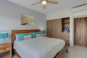 Ein Schlafzimmer mit einem hölzernen Bett, einem Nachttisch, einem Deckenventilator, einem Kleiderschrank und einem Gemälde an der Wand.