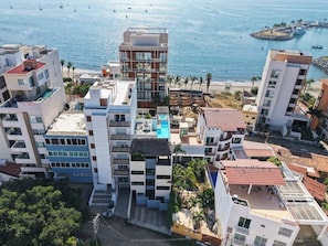A coastal residential area with modern buildings, a swimming pool, and a marina in the background. - Family oasis near the sea - La Cruz Encantada 2A (La Cruz de Huanacaxtle)