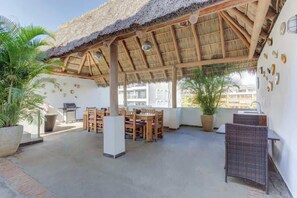 An outdoor patio with a thatched roof, wooden furniture, and potted plants. - Family oasis near the sea - La Cruz Encantada 2A (La Cruz de Huanacaxtle)