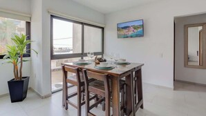 A dining area with a table set for two, a potted plant, and a window with a view. - Family oasis near the sea - La Cruz Encantada 2A (La Cruz de Huanacaxtle)