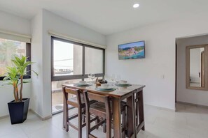 A dining area with a table set for two, a potted plant, and a window with a view. - Family oasis near the sea - La Cruz Encantada 2A (La Cruz de Huanacaxtle)