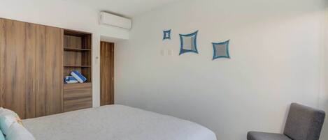 A bedroom with a bed, a chair, a wardrobe, and a ceiling fan.