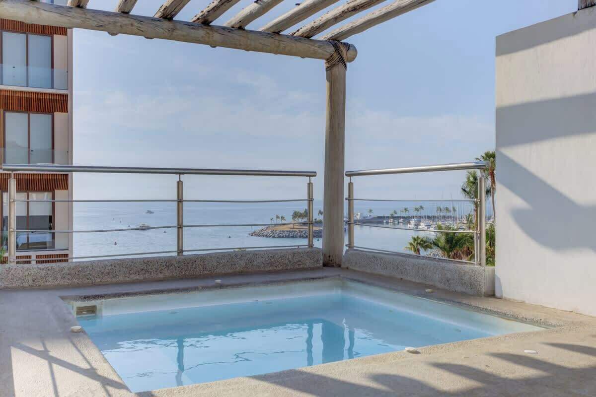 A pool area with a view of the sea and a building with a balcony.
