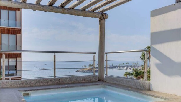 A pool area with a view of the sea and a building with a balcony. - Family oasis near the sea - La Cruz Encantada 2A (La Cruz de Huanacaxtle)