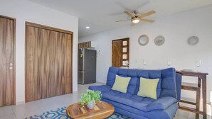 A living room with a blue sofa, a wooden coffee table with a plant, and a patterned rug. - Family oasis near the sea - La Cruz Encantada 1A (La Cruz de Huanacaxtle)