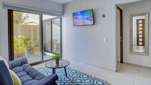 A modern living room with a sofa, a coffee table, and a TV mounted on the wall. - Family oasis near the sea - La Cruz Encantada 1A (La Cruz de Huanacaxtle)