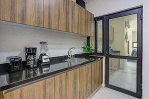 A modern kitchen with wooden cabinets, a black countertop, a coffee maker, a blender, and a sink. - Family oasis near the sea - La Cruz Encantada 1A (La Cruz de Huanacaxtle)