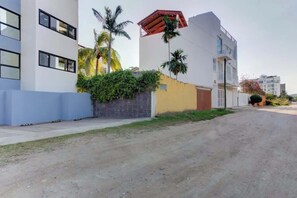 A modern building with a flat roof, large windows, and a paved driveway. - Family oasis near the sea - La Cruz Encantada 1A (La Cruz de Huanacaxtle)