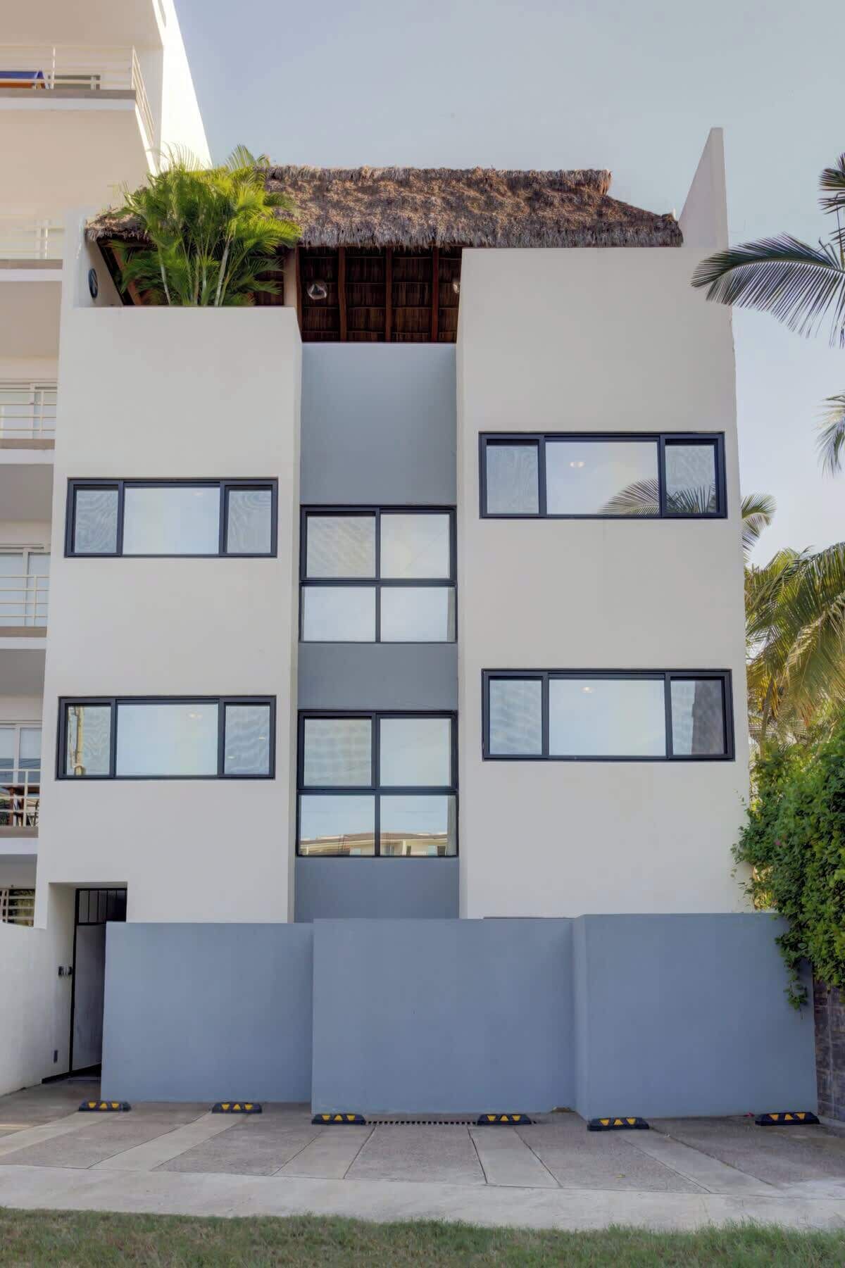 Un immeuble moderne à plusieurs étages, doté de grandes fenêtres et d’un toit plat.