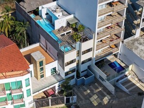 A multi-story building with balconies, a rooftop pool, and a swimming pool. - Family oasis near the sea - La Cruz Encantada 1A (La Cruz de Huanacaxtle)