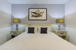 A bedroom with a bed centered between two nightstands, each with a lamp and a small drawer. A framed artwork hangs above the bed. - Family oasis near the sea - La Cruz Encantada 1A (La Cruz de Huanacaxtle)