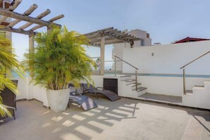 Eine Dachterrasse mit Palme, einer Pergola und einem Pool.