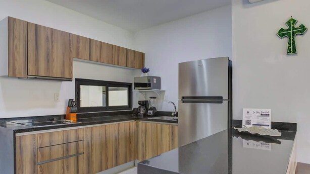 Una cocina moderna con armarios de madera, un refrigerador de acero inoxidable y una encimera negra.