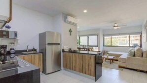 Una cocina moderna con una isla central, un refrigerador y una zona de comedor con un sofá y una mesa de centro.