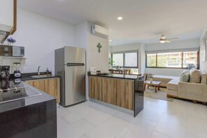 Eine moderne Küche mit Kochinsel, Kühlschrank und Essbereich mit Sofa und Couchtisch.