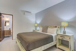 Ein Schlafzimmer mit einem Bett, Nachttischen, einer Lampe und einer Wand-Klimaanlage.