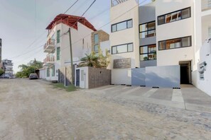 Ein mehrgeschossiges Wohngebäude mit flacher Fassade, einem gut sichtbaren Eingang und einem kleinen Parkplatz.