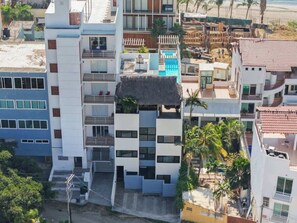 Un immeuble à plusieurs étages doté de balcons, d’une piscine et d’une structure de toit en chaume.