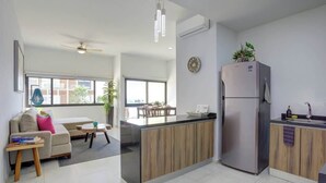 A modern kitchen with a built-in island, a refrigerator, and a dining area with a table and chairs. - Family oasis near the sea - La Cruz Encantada 3A (La Cruz de Huanacaxtle)