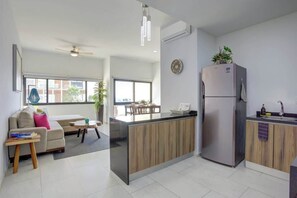 Eine moderne Küche mit integrierter Kochinsel, einem Kühlschrank sowie einem Essbereich mit Tisch und Stühlen.