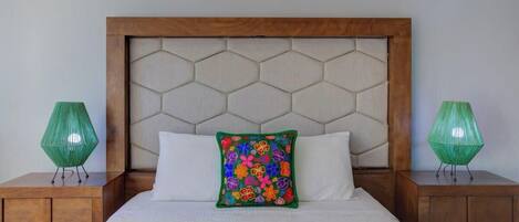 A bed with a wooden headboard, two nightstands, and a colorful decorative pillow.