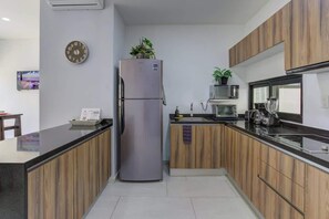 Eine moderne Küche mit einem Edelstahlkühlschrank, Holzschränken, einer Mikrowelle und einem Spülbecken.