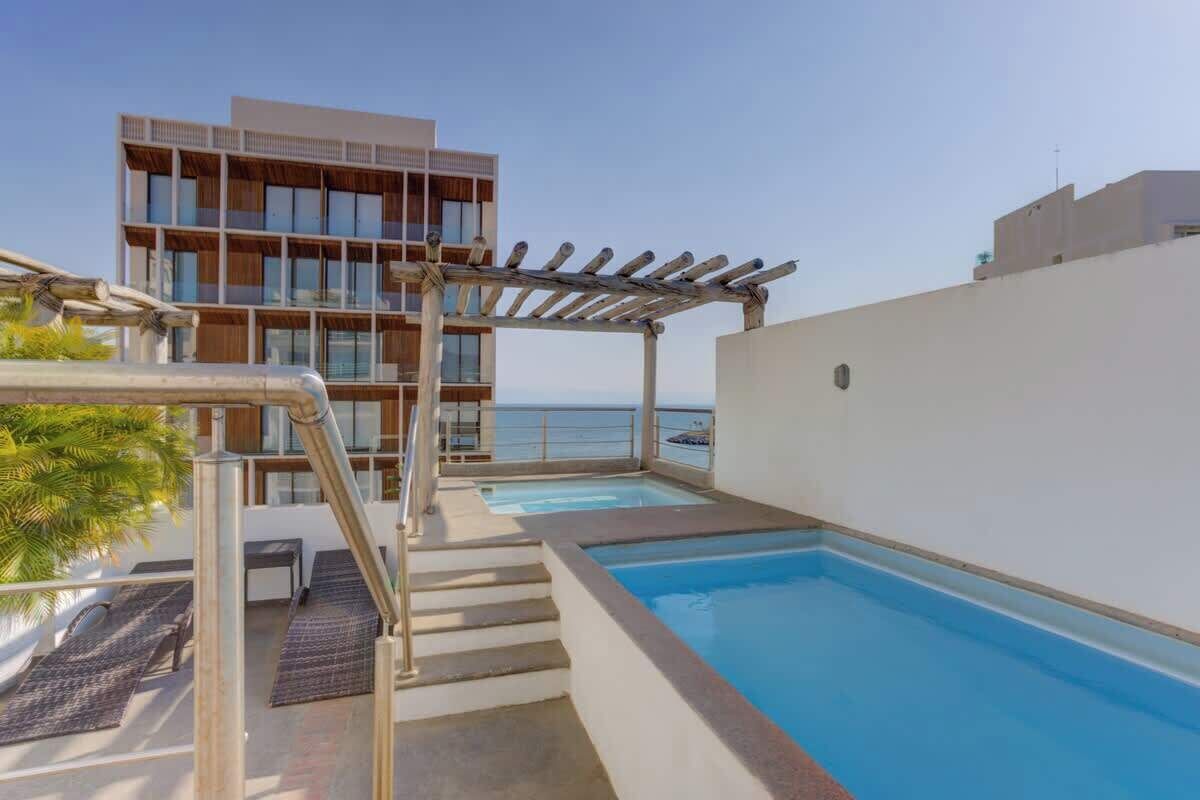 Une piscine sur le toit, agrémentée d’une pergola, d’un escalier et offrant une vue sur la mer.