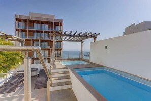 Ein Pool auf dem Dach mit einer Pergola, einer Treppe und Blick aufs Meer.